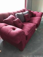Front view of red Ethan Allen sofa showcasing tufted back and pillows.