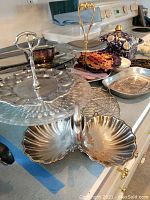 Kitchen counter showing multiple metal serving trays, tiered and divided trays, and a decorative ceramic teapot.