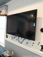 Samsung flat screen TV mounted on wall, showing front view with music note wall decals underneath.