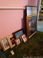 Framed artworks leaning against walls with visible variety in frame styles and artwork sizes.