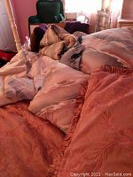 Photo of multiple pillows with shams and a comforter on a bed, showing fabric texture and colors.