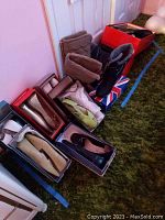 Multiple pairs of winter boots and slip-on flats in shoe boxes and out, arranged on the floor.