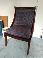 Front view of wood-framed chair with purple patterned upholstery, showcasing the slightly curved backrest and seat cushion placed on a carpeted floor.