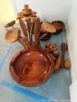 Wooden salad bowls, large serving bowl, and multiple wooden salad utensils displayed together on the floor.