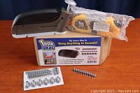 Opened Insta Hang hanging tool on table with original box and yellow plastic parts in bubble wrap