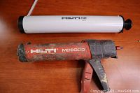 Hilti MD2000 caulking tool and Hilti HIT accessory placed on wooden surface, showing overall lot contents.