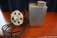 High intensity discharge grow light housing with power cords on wooden table.