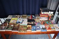 Wide view of book lot arranged on a table, showing a collection of 34 books with diverse titles and colorful covers