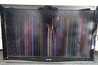 Front view of Sharp 46 inch Aquos TV with a severely cracked and broken screen showing vertical multicolor lines.