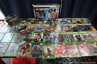 Full spread of Xbox game titles showing boxed LEGO Dimensions, assorted Xbox 360 games, and original Xbox titles on table
