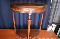 Full view of the wooden half circle side table showing carved apron, turned legs, and curved stretcher base.