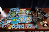 Full view of assorted Pokemon cards, player’s guides, collectible Pokeball items, and transparent plastic display containers with artwork.