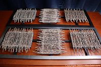 Two wood décor panels laid horizontally on a wooden surface showing the overall design of whitewashed twig clusters on rectangular black frames.