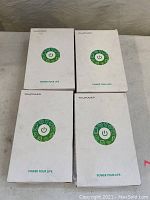 Four Ravpower car jump starter boxes stacked on surface, showing front packaging with green power button and logo.