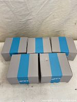 Five UpHere branded grey and blue boxes containing the fans, arranged in two rows on a beige surface.