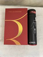 Red and gold box labeled 'Wine Accessorise' next to black cylindrical packaging for electric wine opener.