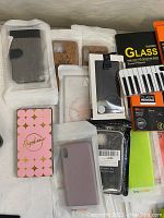Various phone cases in packaging and it's including cloth cleaning wipes and a wallet style phone case.