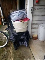 Image of white woven style baby bassinet stacked with baby mattress and comforter set in plastic packaging.