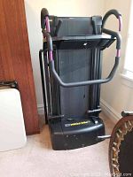 Folded upright ProForm treadmill showing front console and handlebars with purple grips, black frame and base unit.