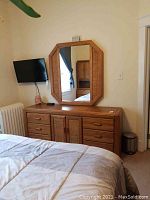 Dresser with six drawers and two center cabinet doors with woven panels topped by a large octagonal framed mirror.