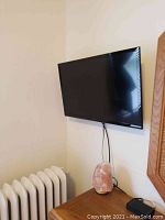 Wall-mounted Insignia 32-inch TV above dresser with power cable visible