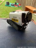 Silver Sony video camera with 30GB HDD, 20x zoom, strap visible, on table outdoors