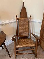Full view of vintage rattan rocking chair with woven seat and backrest, showing wooden frame and armrests.