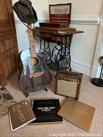 Overall lot view showing guitar with hat, amp, and course materials
