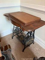 Vintage Montgomery Ward sewing machine table showing wooden top and cast iron base with pedal.