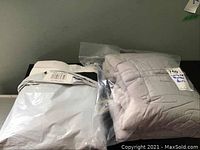 Both items side by side: sealed white bed skirt and folded grey weighted blanket.