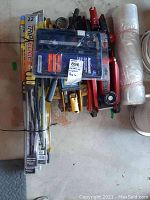 Top view of all items showing hydraulic jacks, electric caliper kit in plastic case, and bundled windshield wiper blades.