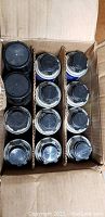 Top view of 12 cans of foam sealant neatly organized in a cardboard box with dividers.