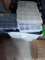 Photo of multiple plastic storage organizers and bins stacked, used to hold assorted hardware items.