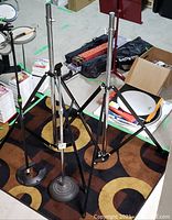 Two heavy-duty metal tripod-style speaker stands and two microphone stands - one round-base and one On Stage MS7325 stackable stand with twist clutch for height adjustment.