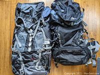 Both backpacks shown side by side on wooden floor. The RWD Killarney with visible mesh pockets and adjustable straps. High Sierra pack marked "45" volume visible on front.