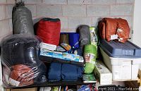 Shelf view of rolled tents, sleeping bags and plastic storage tote