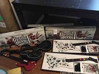 Two white X-plorer controllers in original Guitar Hero II boxes at rear, two black Les Paul style and one red controller in front