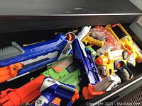 Drawer with multiple Nerf blasters showing various brightly colored models packed together.