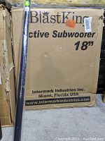 Cardboard box labeled "BlastKing Active Subwoofer 18" with attachment shaft leaning against it