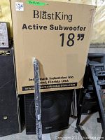 Subwoofer box labeled BlastKing Active Subwoofer 18" with speaker and attachment shaft in front.