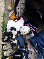 Assortment shot showing leg pads, jerseys, skates, helmet, and gear bag on floor