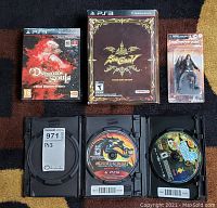 Five items arranged: three game cases, one figure box, and three open case discs below