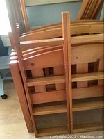 Two wooden bunk beds disassembled and stacked vertically with ladders shown in front. Light wood with scratches and wear marks.