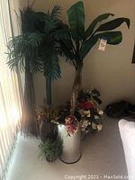 Two tall faux trees placed next to each other with various floral arrangements and containers around their base