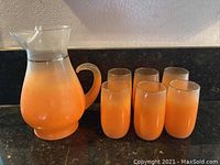 Full set photo showing one pitcher and six matching cups in retro orange gradient on a black countertop.