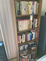 Bookshelves filled with various hardcover and paperback books arranged in rows, some horizontally stacked at bottom.