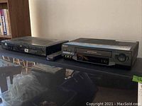 Two black Sony players, one DVD and one VHS, placed side by side on a surface.