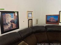 Wall with six framed artworks above sectional sofa, showing variety in size, style, and framing.