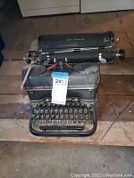 Front view of Smith Corona manual typewriter showing keys and casing with a tag attached.