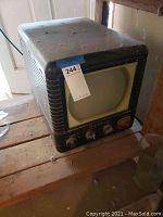 Full side view of the vintage Admiral tube TV showing the screen and ribbed casing with an auction tag attached.